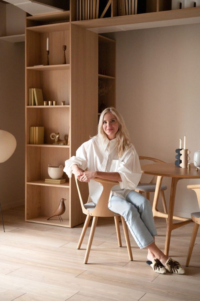 Dizajnérka Yana Molodykh sediac na stoličke v byte.