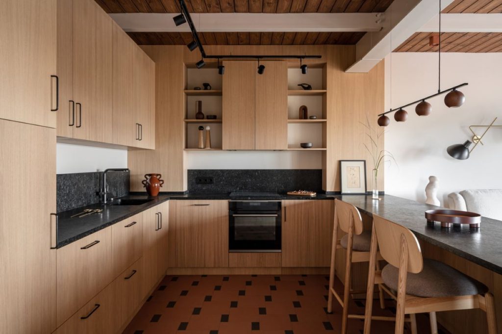 Kuchynská časť bytu s drevenou kuchynskou linkou a pultom, slúžiacim ako stôl.