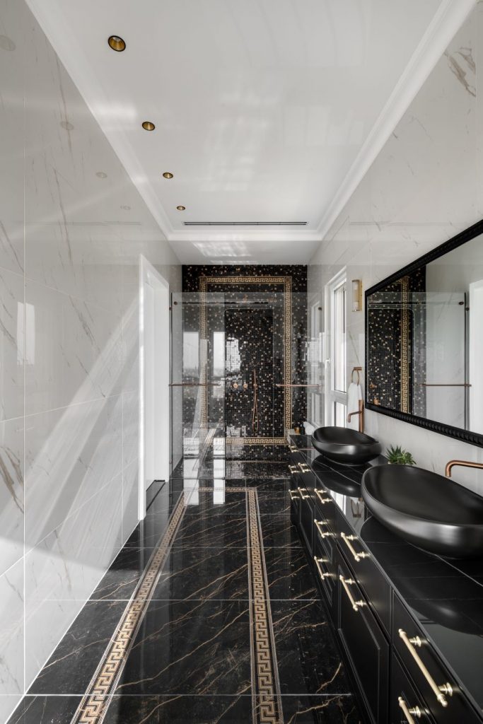 Pohľad do čierno-bielo-zlatej luxusnej kúpeľne s ornamentom.