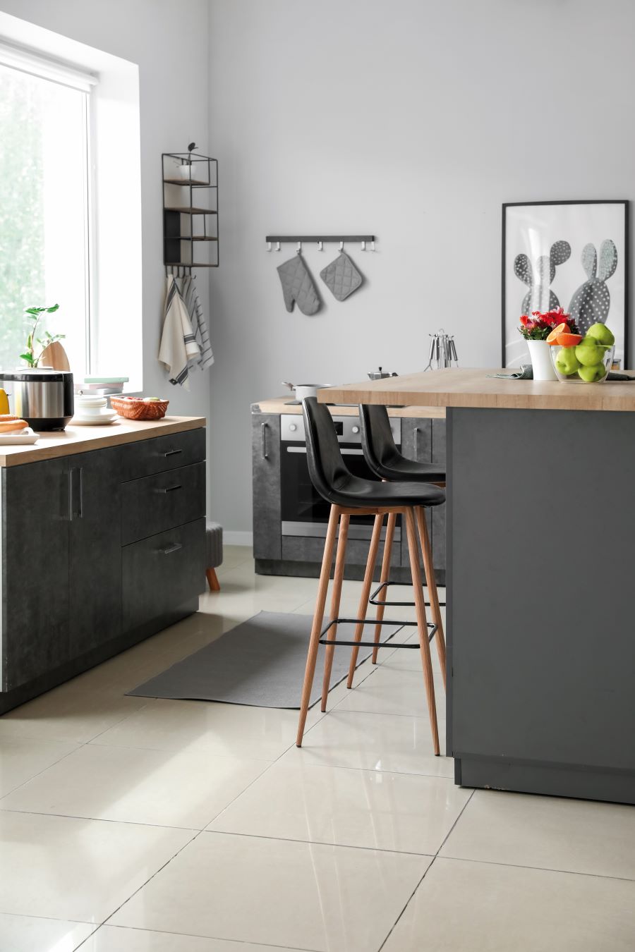 Záber do čierno-šedej modernej kuchyne s linkou a barovým pultom so stoličkami.