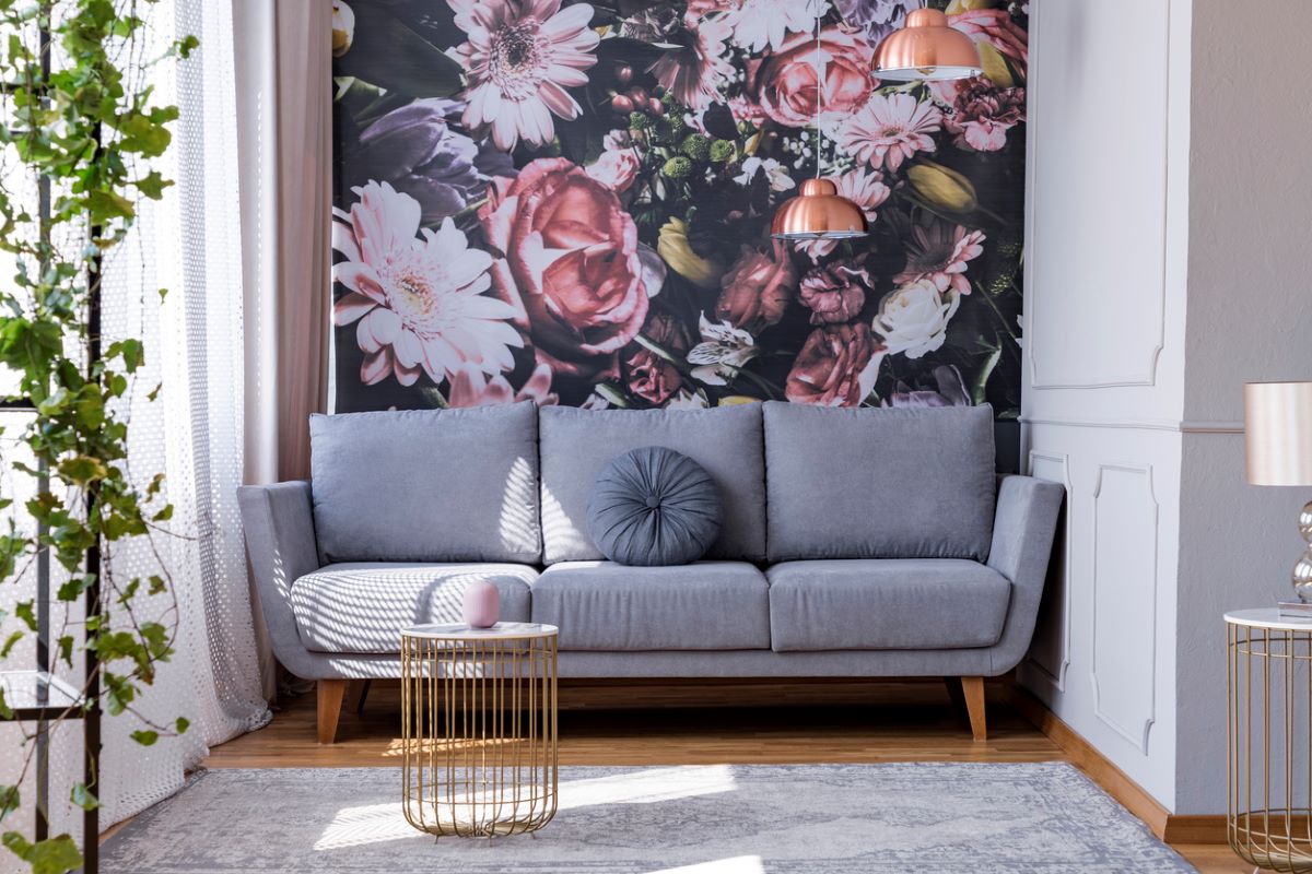 Sivá sedačka pri stene s kvetinovou tapetou.
