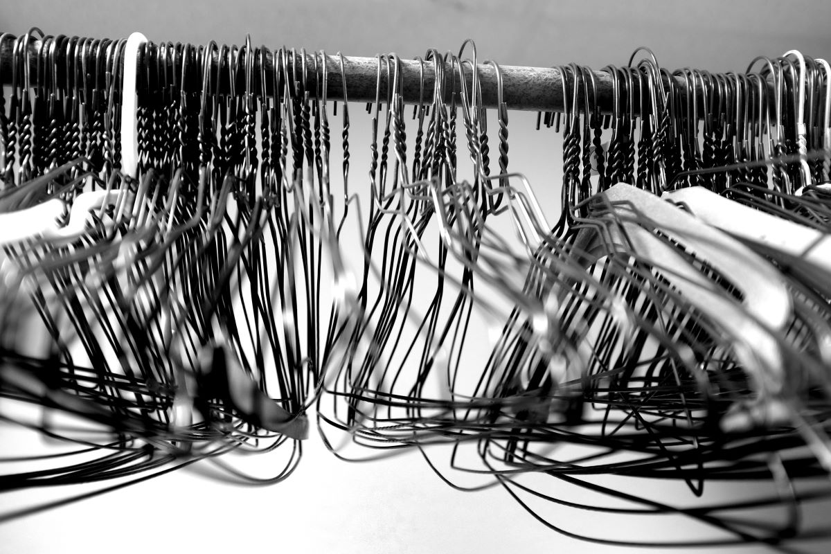 Detail na množstvo drôtených vešiakov na tyči.