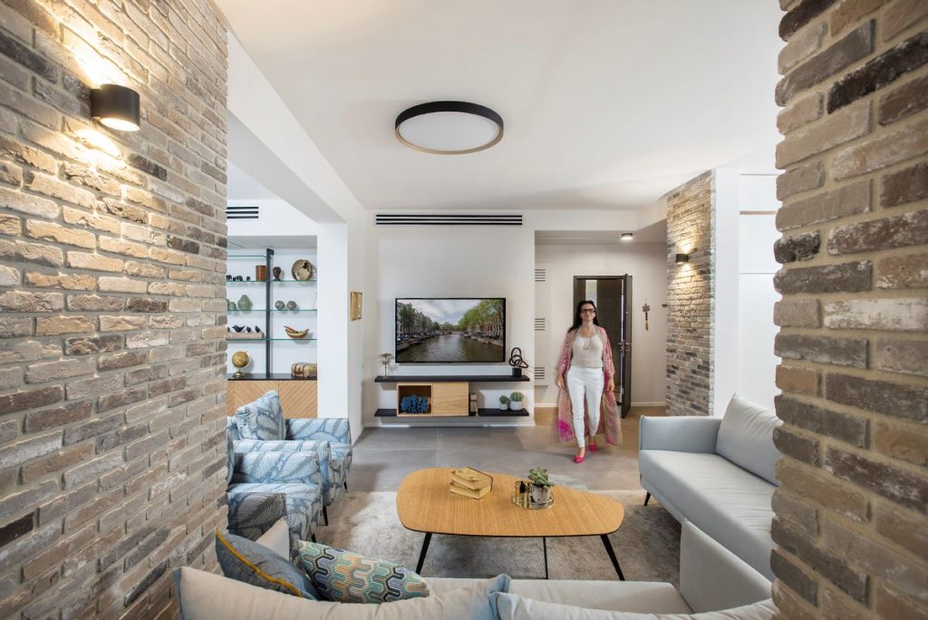 Pohľad do modernej obývačky so sedačkami, stolíkom a priznanou tehlou na stenách.