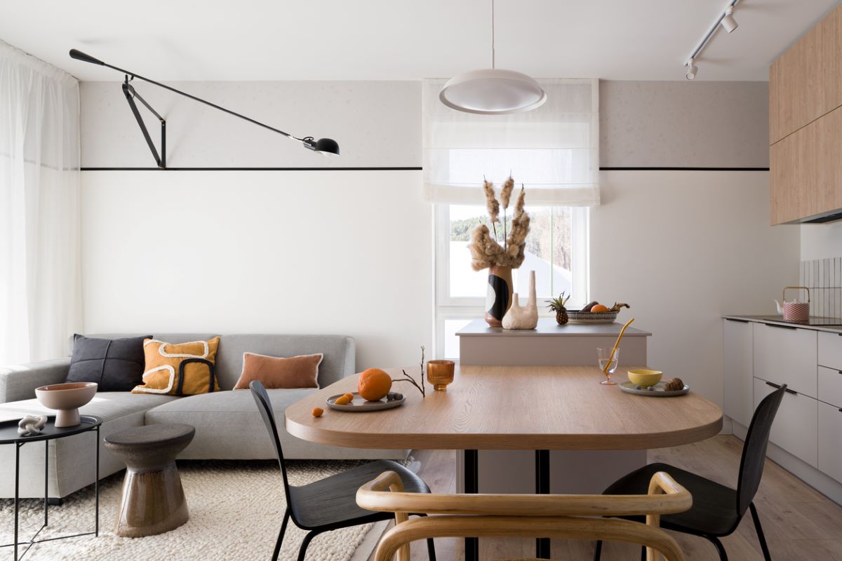Časť minimalisticky zariadeného malého interiéru s kuchynksou linkou, stolom a sedačkou.