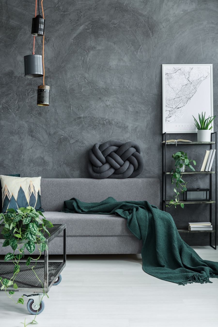 Interiér so sivou stenou a sedačkou a tmavozelenou dekou.