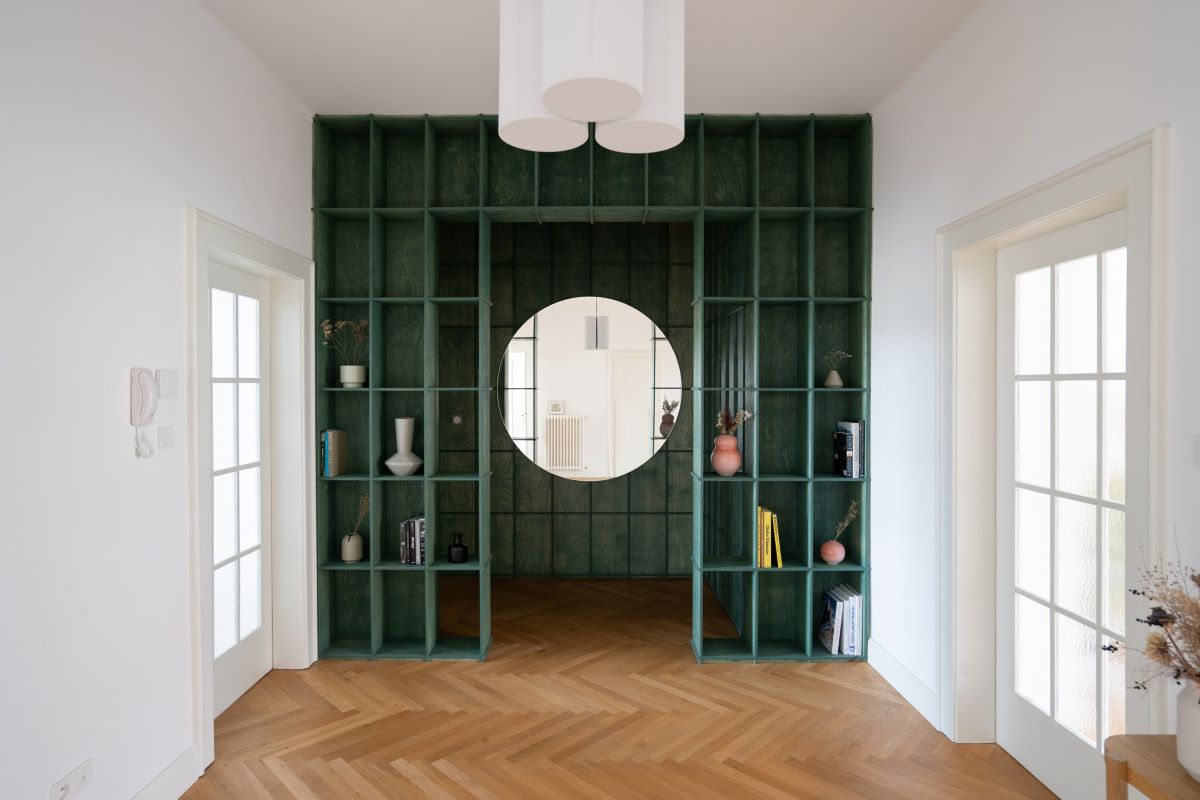 Pohľad na zelené zádverie bytu s knižicou a zrkadlom.
