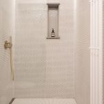 Záber na sprchovací kút v kúpeľni s mosadznými prvkami.