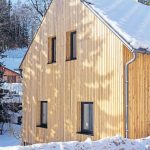 Časť domu v Krkonošiach s drevenou fasádou v zime.