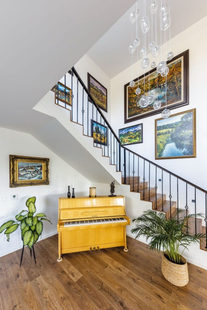 Záber na priestor pod schodami so žltým klavírom.