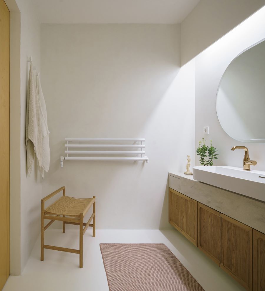 Časť kúpeľne s dvojumývadlom na skrinke a drevenou stoličkou.