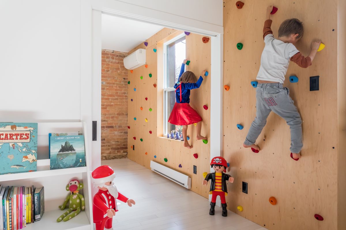 Chlapec a dievča lezú po lezeckej stene v detskej izbe.
