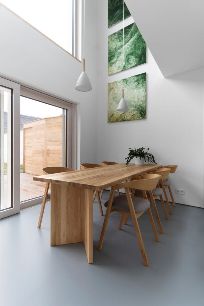 Záber na drevený jedálenský stôl so stoličkami pri kuchyni.