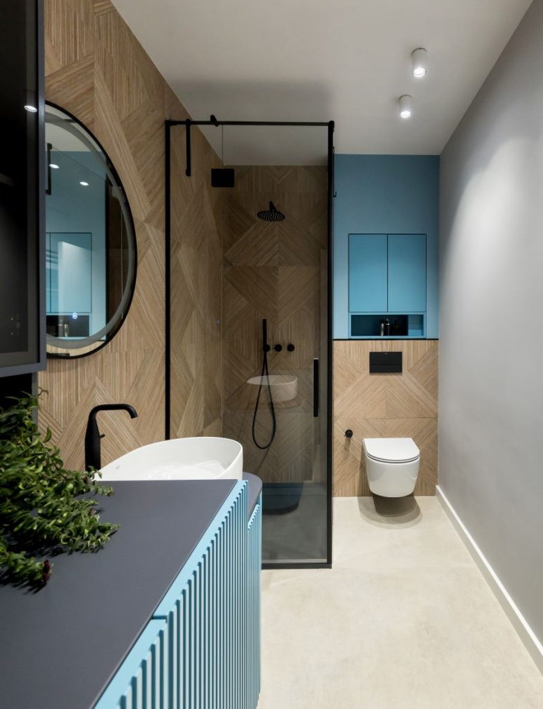 Pohľad do modro-čierno-bielej kúpeľne so sprchovacím kútom a toaletou.