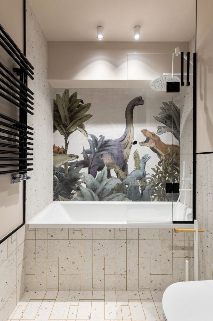 Záber na kombinovanú vaňu so sprchou a obrazom dinosaurov.
