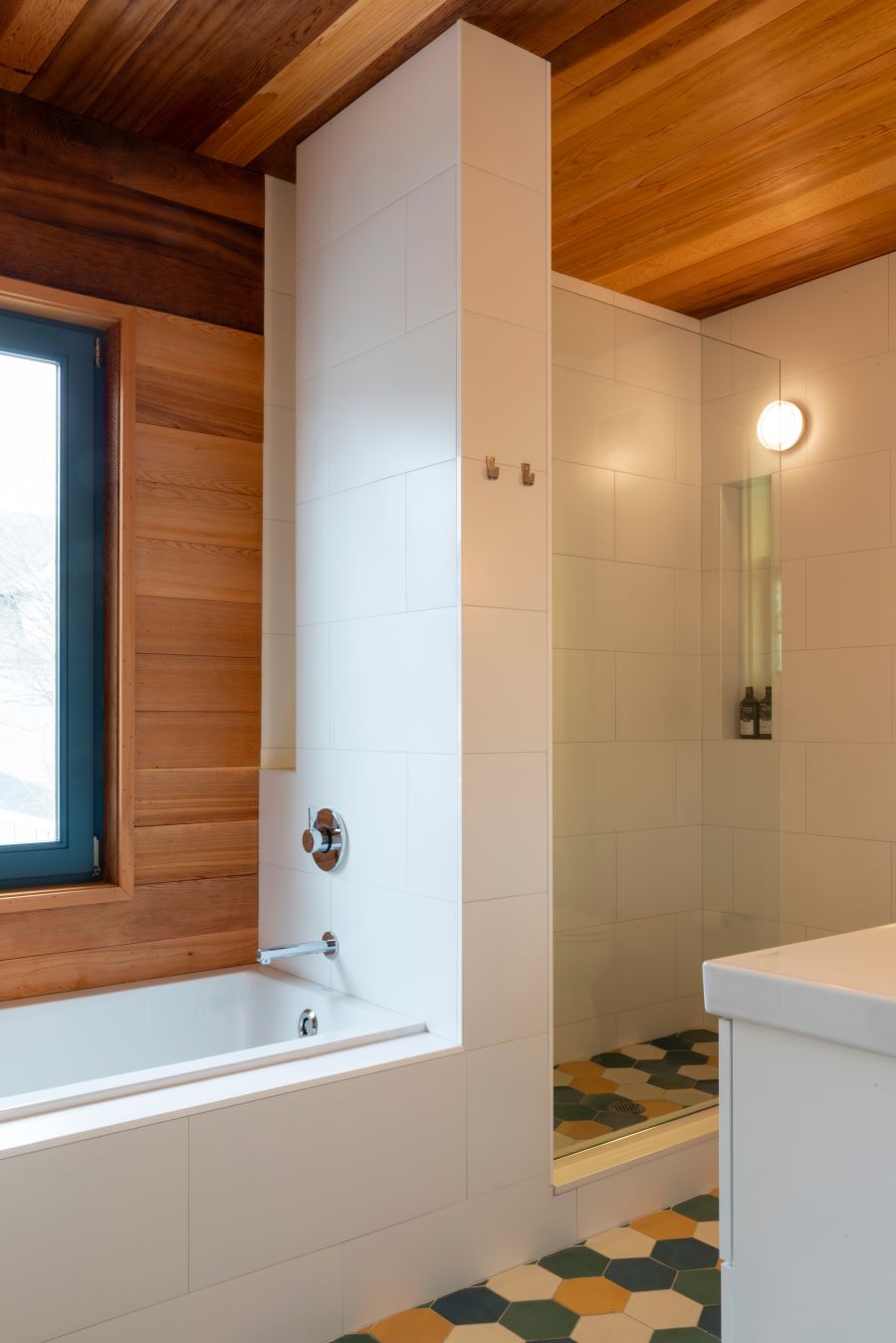 Časť kúpeľne s vaňou, sprchovým kútom a farebnými dlaždicami.