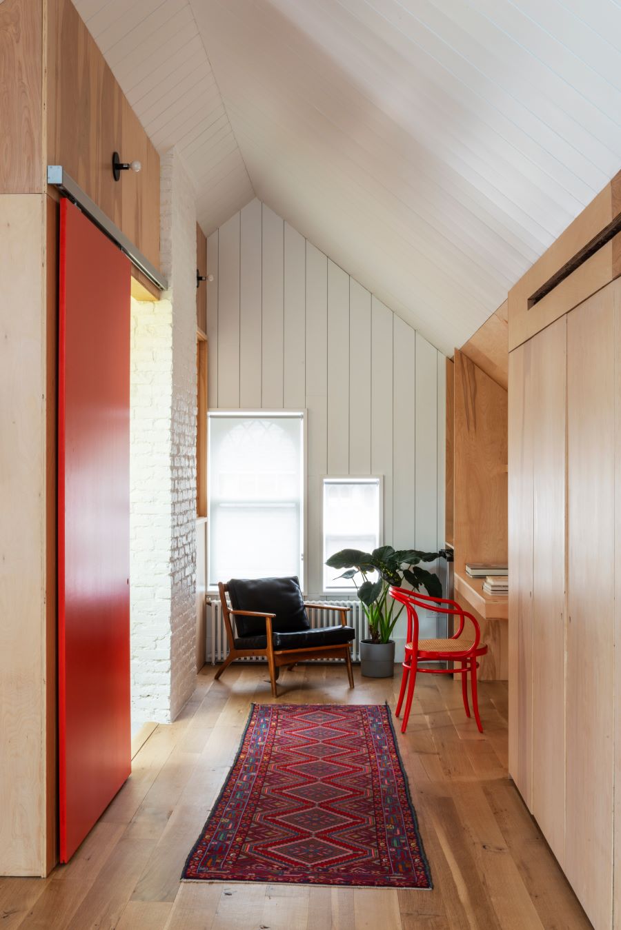 Časť interiéru so stoličkami, kobercom a červenými posuvnými dverami.
