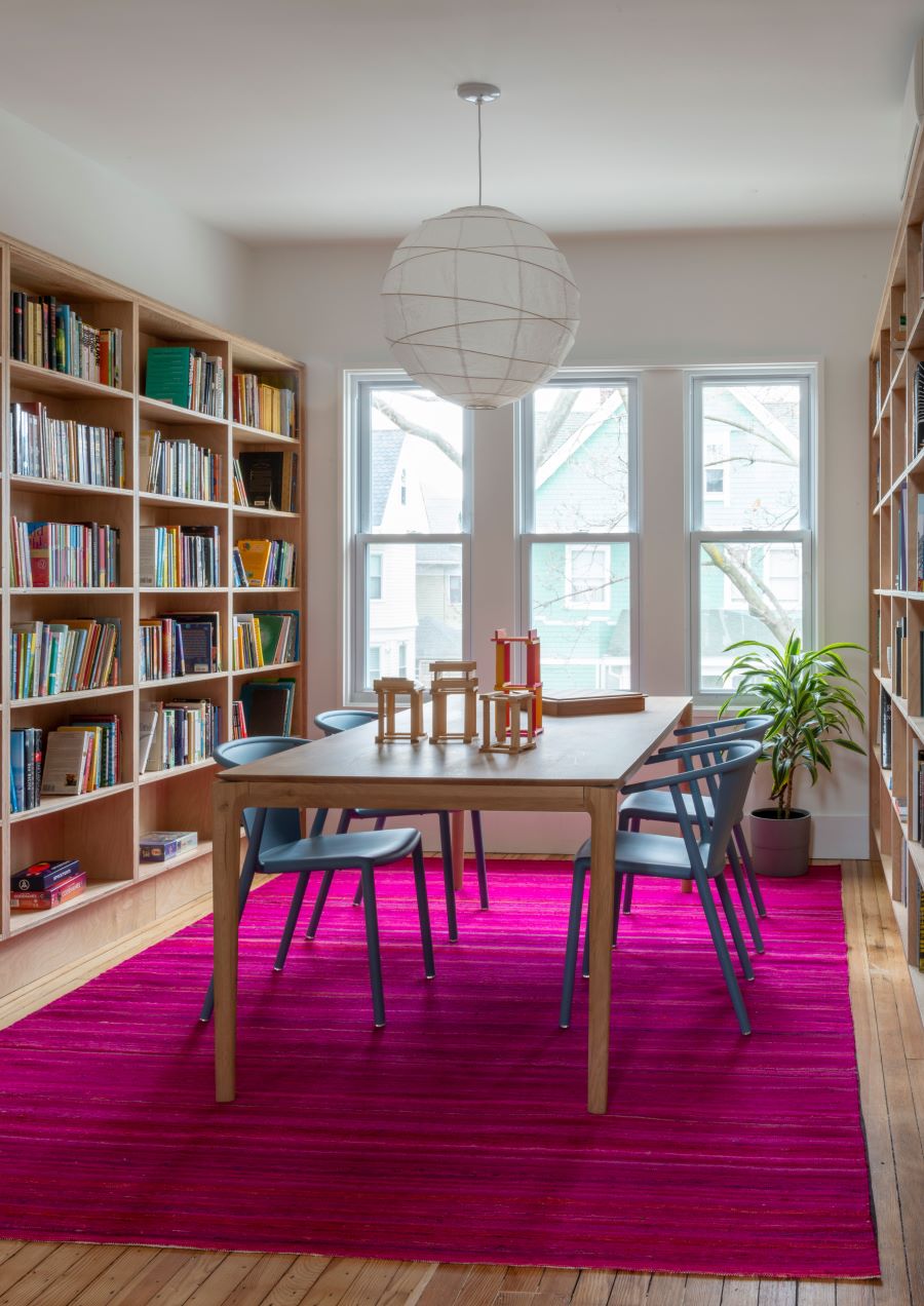 Knižnica s dreveným stolom a kobercom.