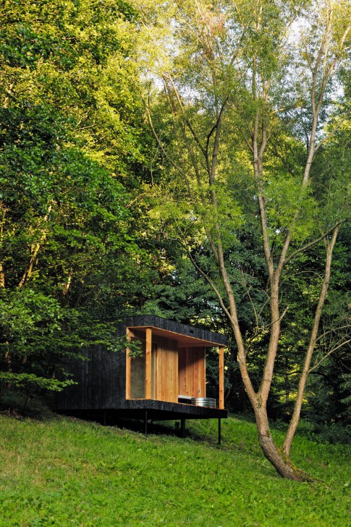 Pohľad na saunu ako oddelenú súčasť chaty Hytta medzi stromami.