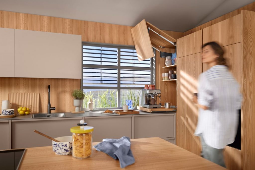 Žena v kuchyni so skrinkou s otvorenými dvierkami.