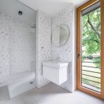 Kúpeľňa na chate so sprchovým kútom, umývadlom a svetlým obkladom.