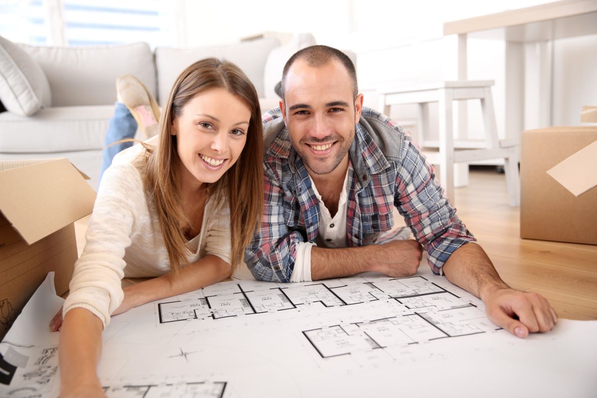 Muž so ženou ležia na zemi a pozerajú sa na pôdorys.