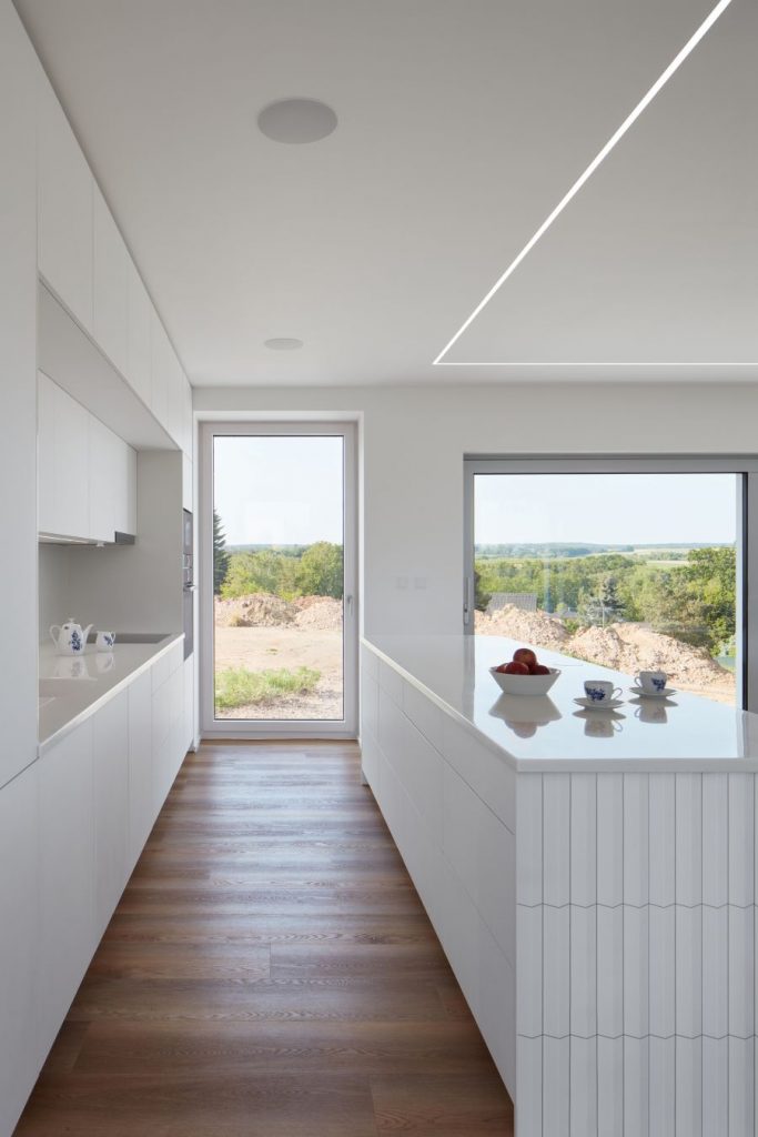 Pohľad na bielu kuchyňu s presklenými dverami na dvor.