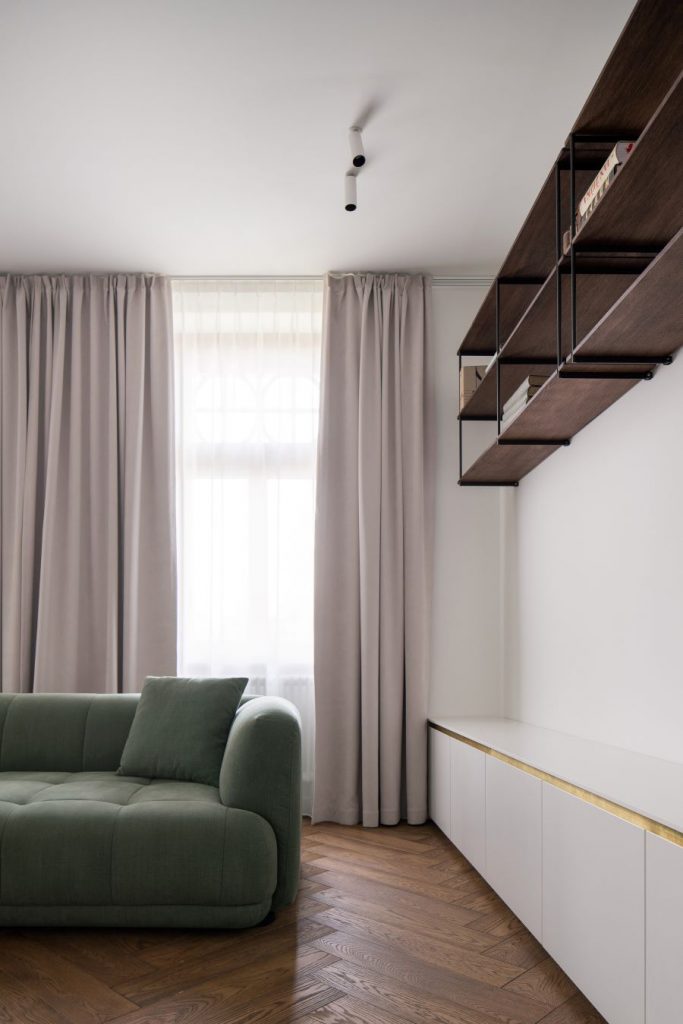 Časť obývačky s nízkymi skrinkami a policami na stene.