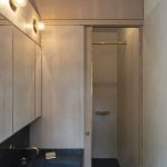 Časť kúpeľne s drevenými skrinkami a posuvnými dverami do sprchovacieho kúta.