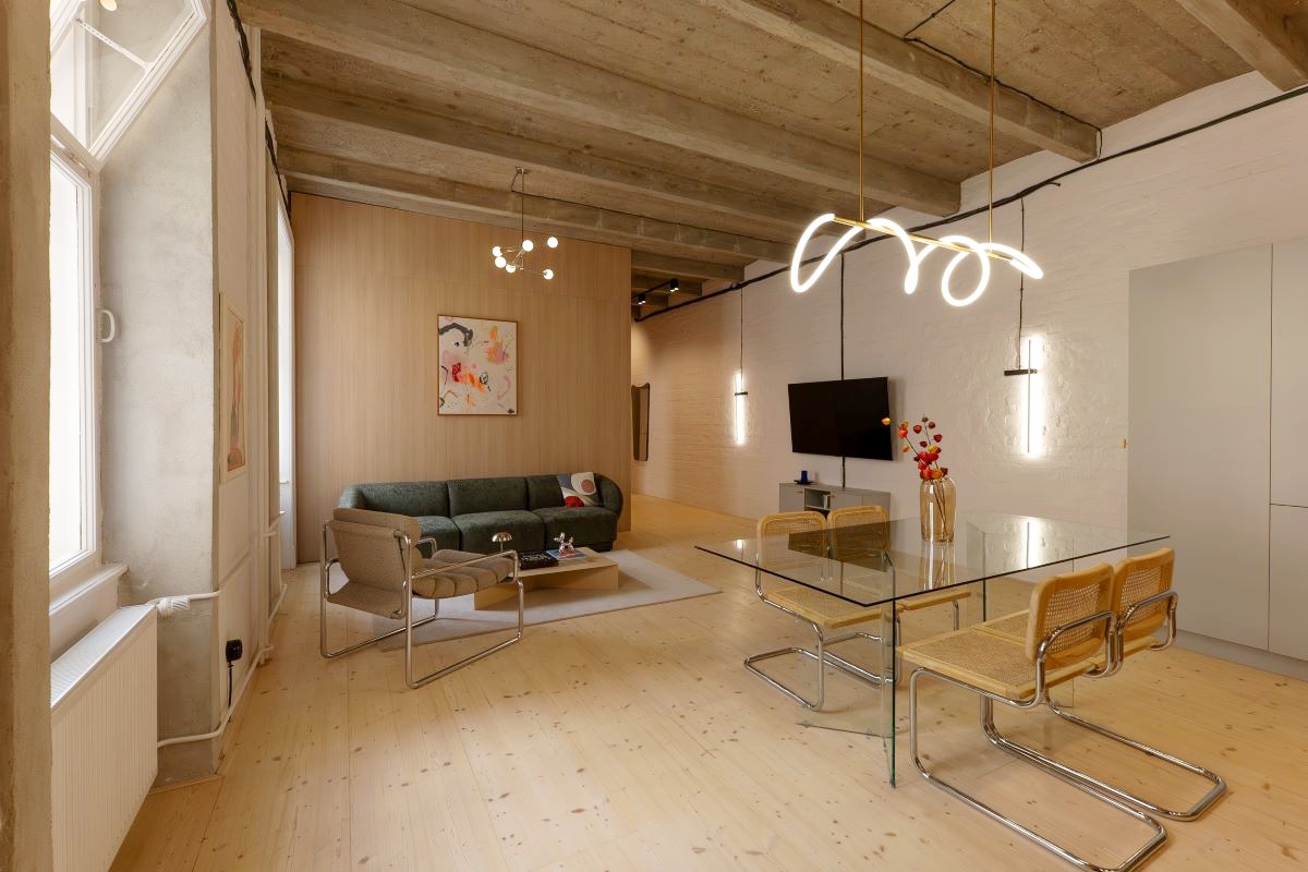 Minimalistická obývačka so sedačkou a kreslom v neutrálnych tónoch.