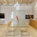 Minimalistiská kuchyňa s mramorovou pracovnou doskou a skleneným jedálenským stolom.