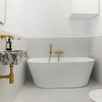 Kúpeľňa do samostatne stojacou vaňou, umývadlom z mramoru Calacatta Viola a zlatými doplnkami.