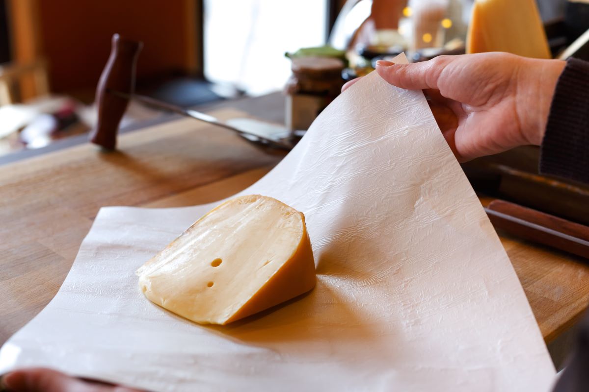 Žena balí kúsok syra do papiera.