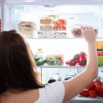 Žena vyťahuje potraviny z chladničky.