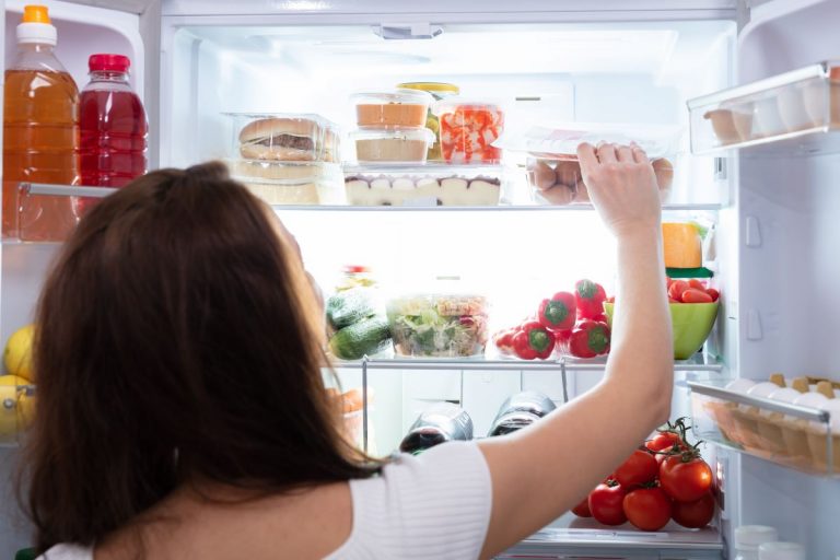 Žena vyťahuje potraviny z chladničky.