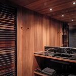 Kúpeľňa s dreveným obložením stien a čiernou mramorovou pracovnou doskou.