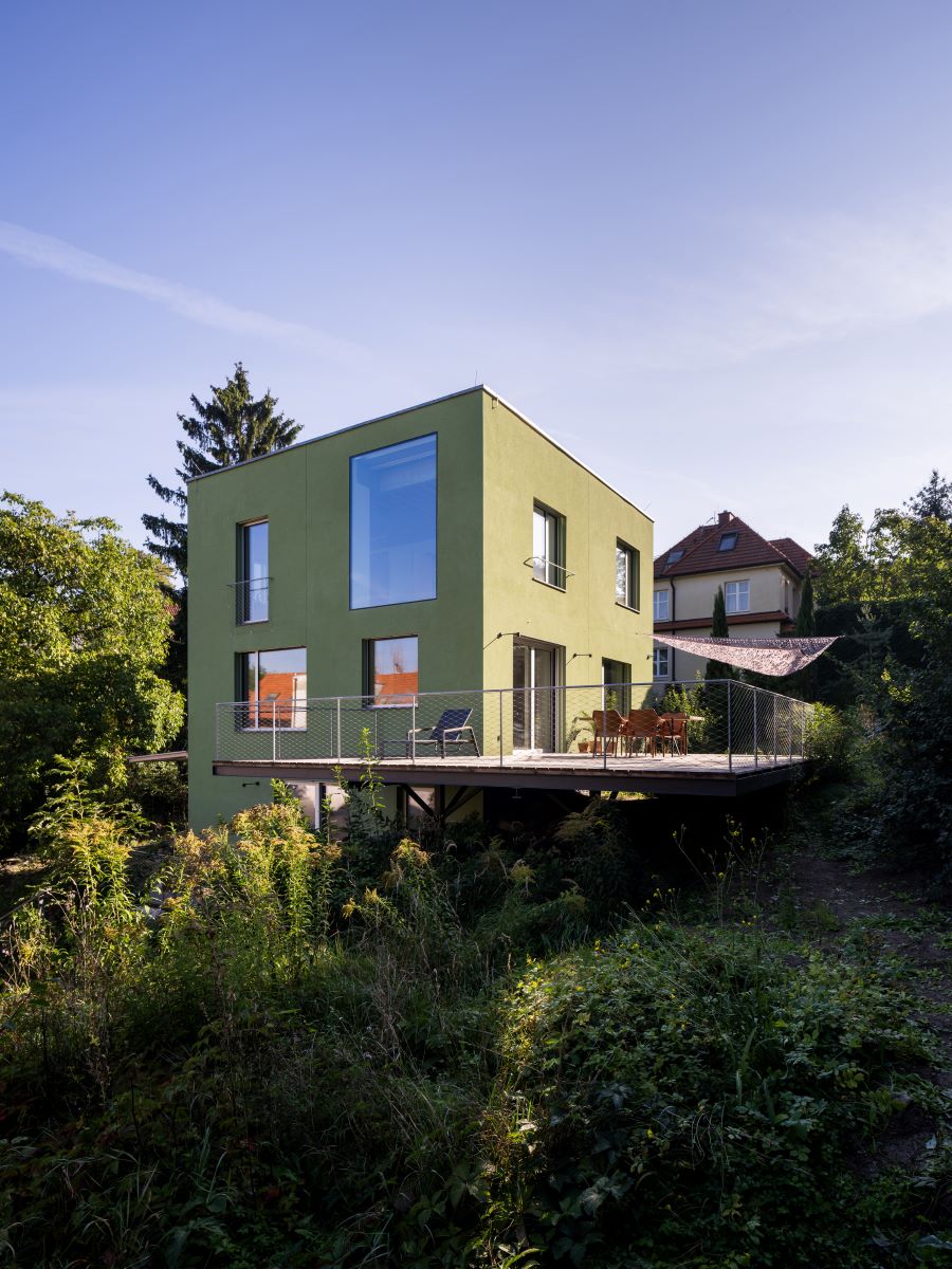 Zelený dom s vysunutou terasou z exteriéru.