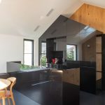 Moderná čierna kuchynská linka v minimalistickom prevedení v stave domčeka.