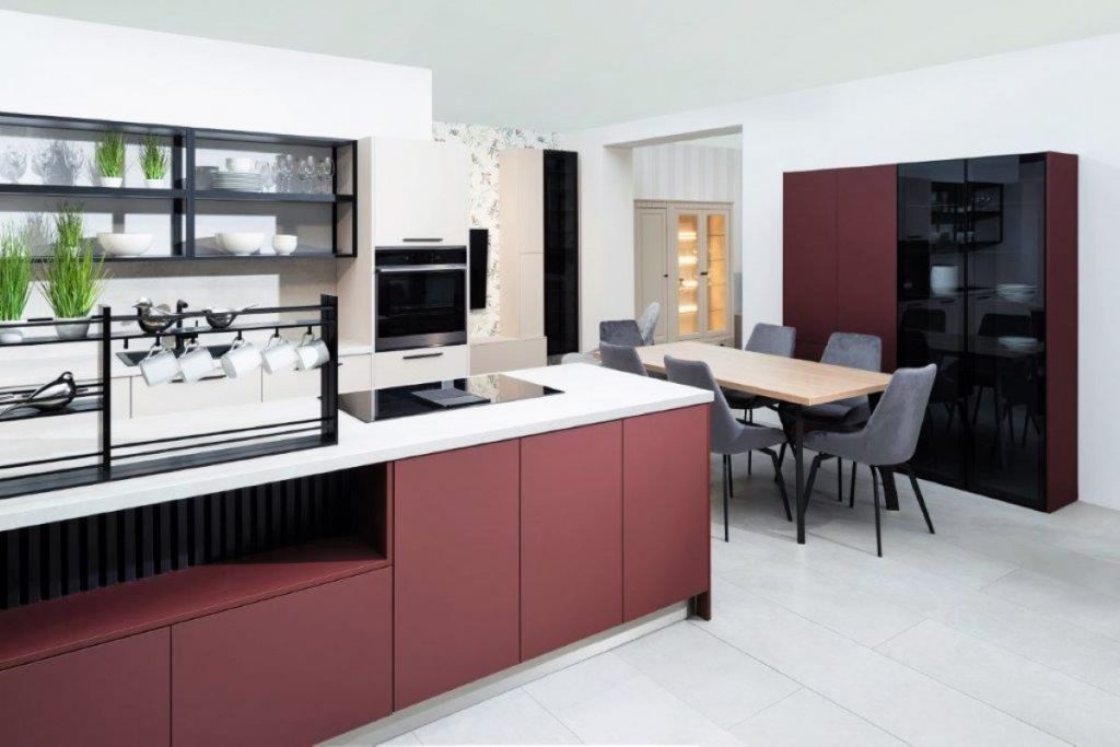 Moderná kuchyňa s kuchynským ostovčekom vo vínovej a pracovnou doskou v bielej farbe, jedálenským stolom a minimalistickou vitrínou s riadom.