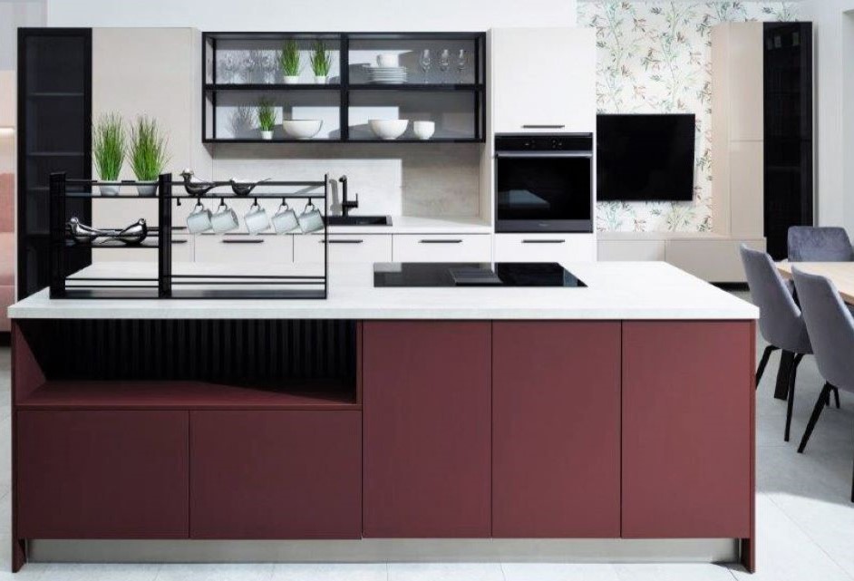 Moderná kuchyňa s bielou linkou a ostrovčekom vo vínovej farbe, kovovým regálom so šálkami a čiernymi policami s presklenými dviekami.