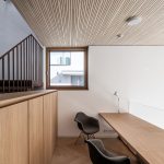 Moderná domáca kancelária s drevenými stropnými panelmi a minimalistickým nábytkom.