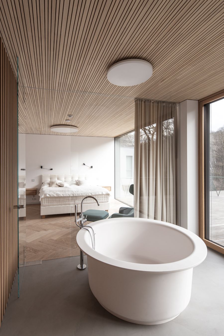 Luxusná kúpeľňa s voľne stojacou vaňou a preskleným výhľadom do spálne.