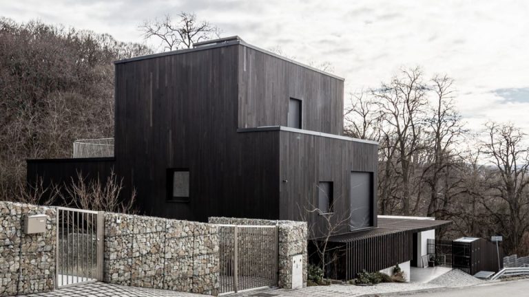Moderný trojposchodový dom s dreveným obložením a minimalistickým dizajnom.