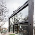 Moderný dom s veľkými sklenenými oknami a záhradou