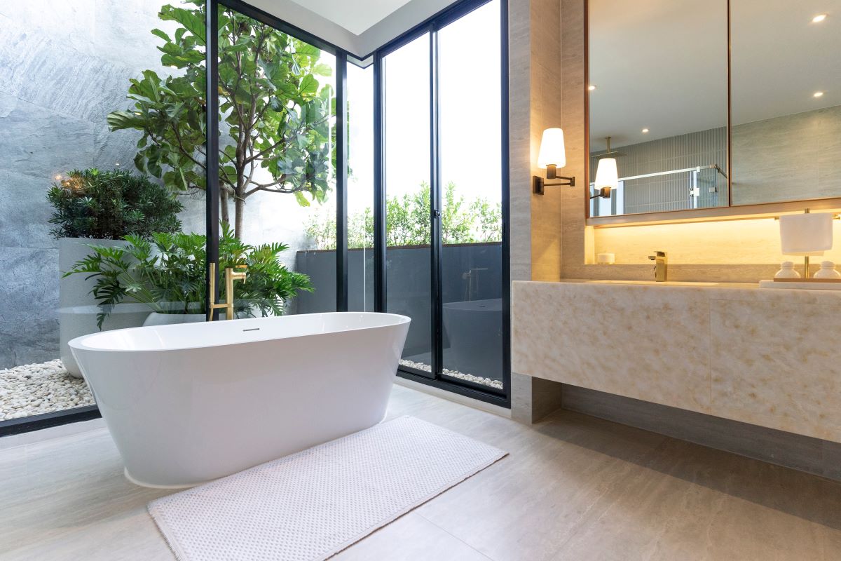 Moderná kúpeľňa s presklenými stenami s výhľadom na balkón, samostatnou vaňou a luxusným zariadením.
