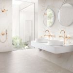 Luxusná kúpeľňa s mramorovým obkladom a mosadznými batériami pri dvoch dizajnových umývadlách.