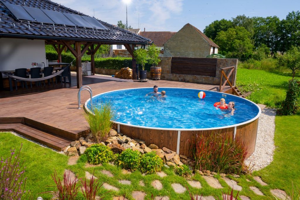 Rodina sa kúpe v okrúhlom bazéne Azuro pri terase rodinného domu.