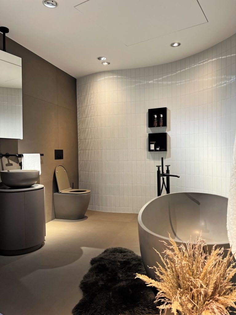 Moderná kúpeľňa s okrúhlou vaňou, tmavým nábytkom a dekoráciami.