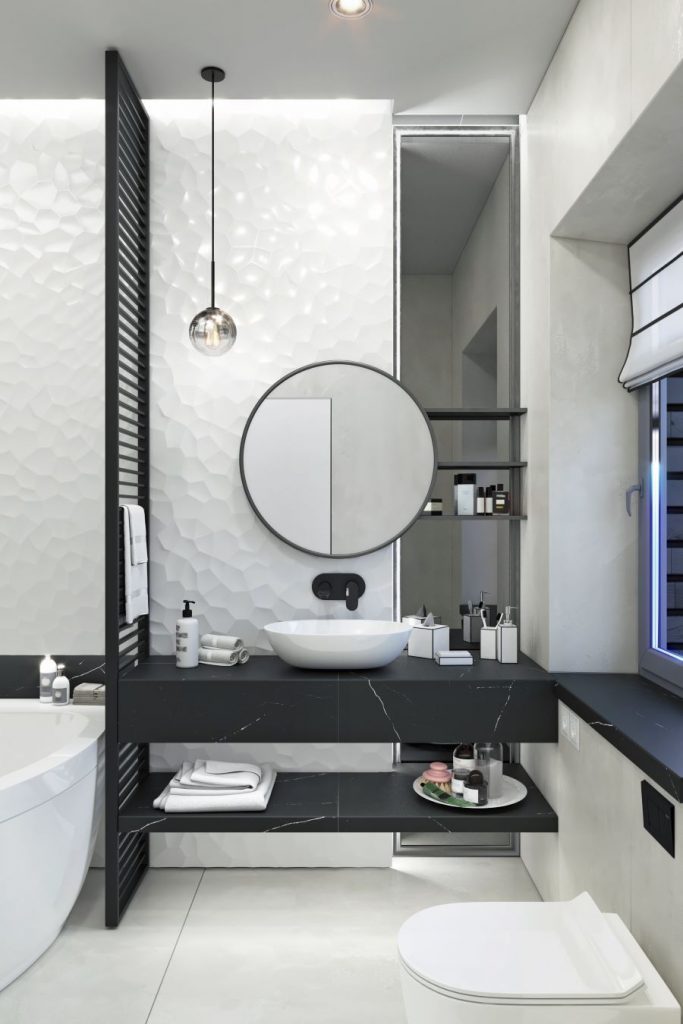 Moderná kúpeľňa s okrúhlym zrkadlom a umývadlom na tmavom pulte s doplnkami.