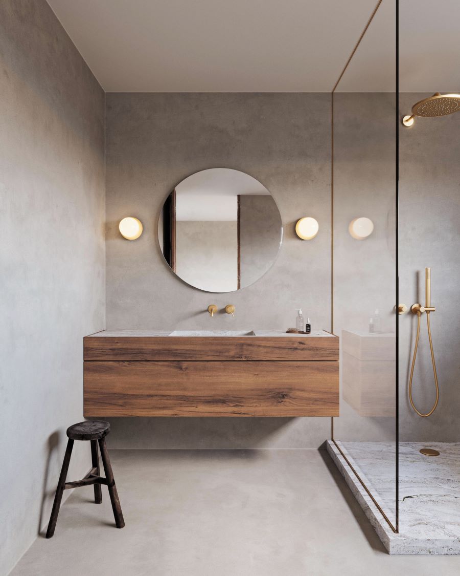 Štýlová kúpeľňa s dreveným nábytkom, veľkým okrúhlym zrkadlom a zlatými armatúrami.