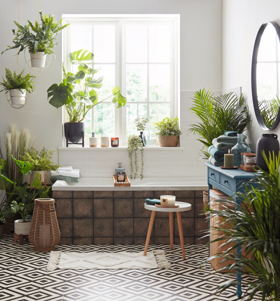 Svetlá kúpeľňa plná zelených rastlín s vaňou, dreveným nábytkom a dekoračnými prvkami.